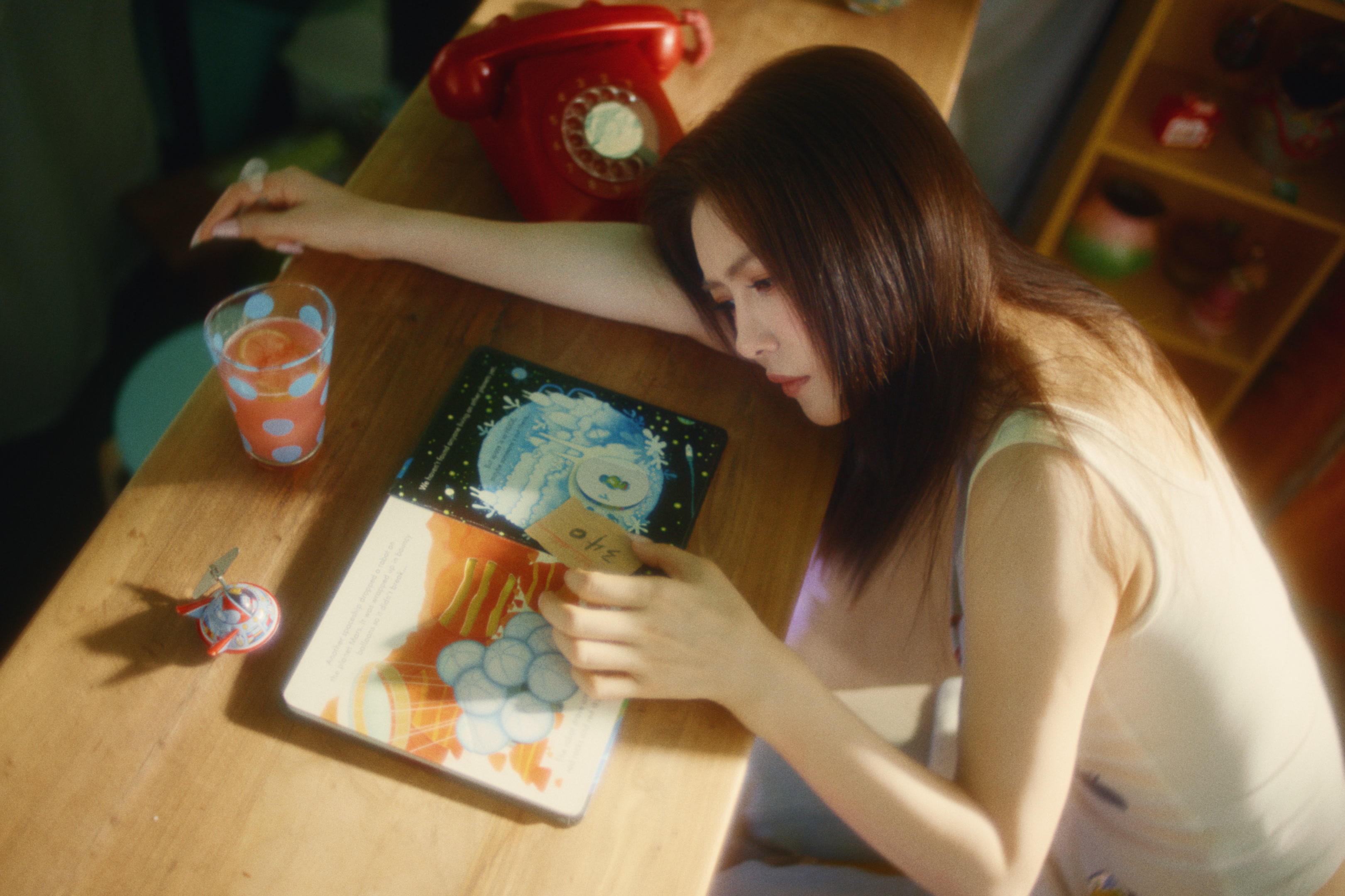 A woman leaning over a table beside a red telephone