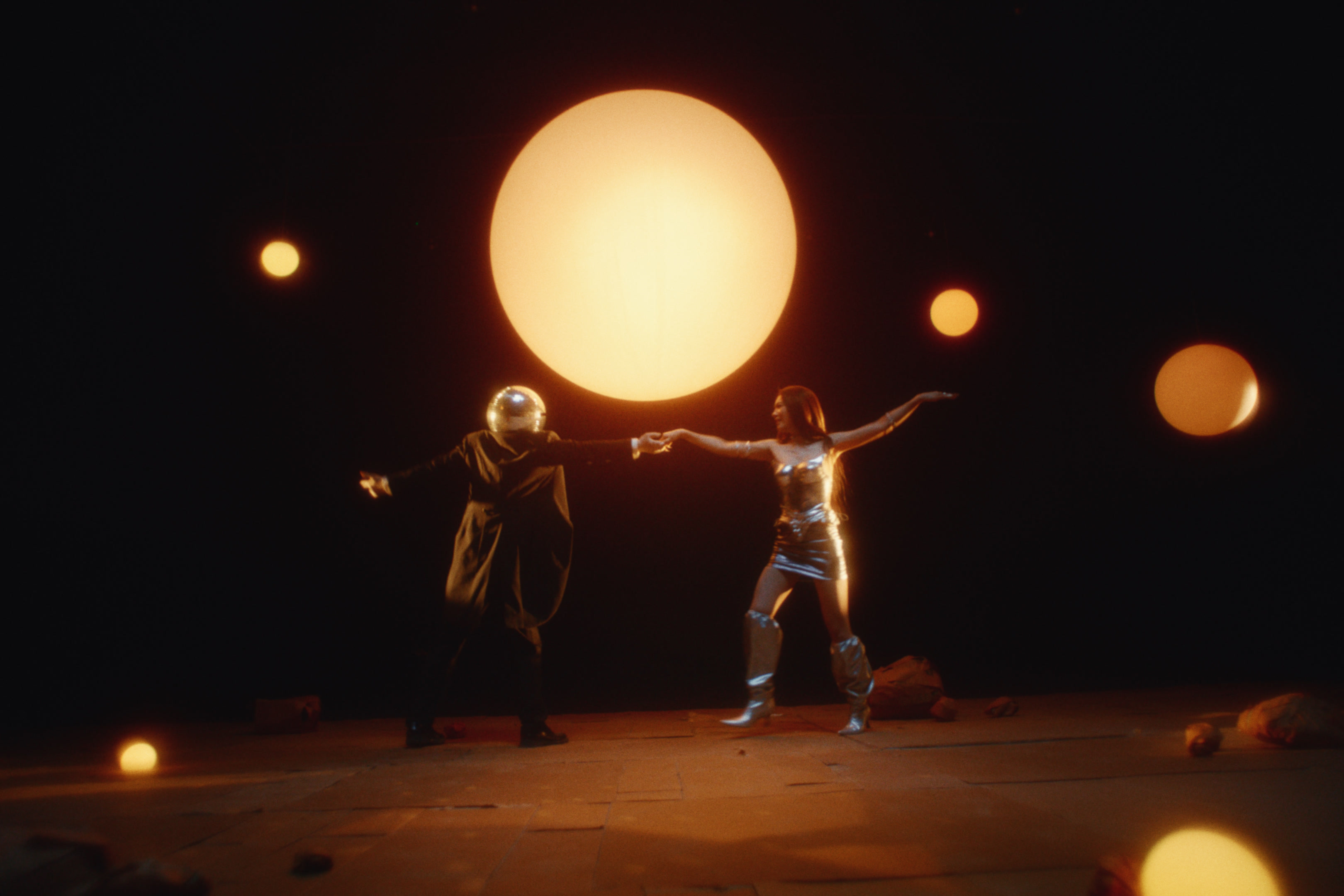 Two figures dancing beneath glowing planets