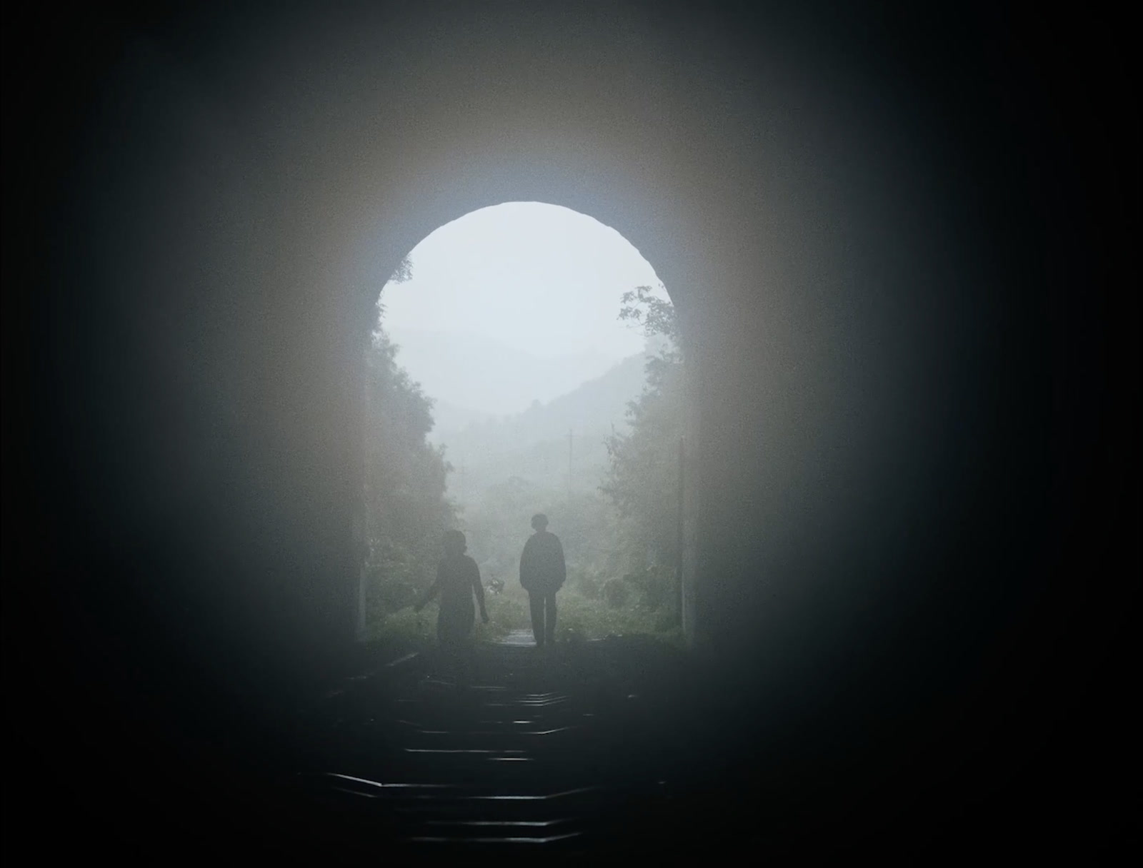 Two figures at the mouth of a tunnel