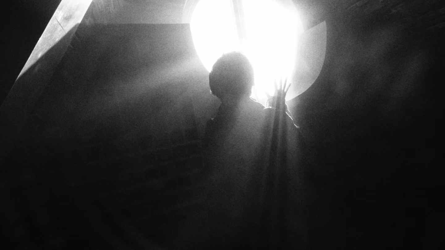 A figure silhouetted against a bright circular light