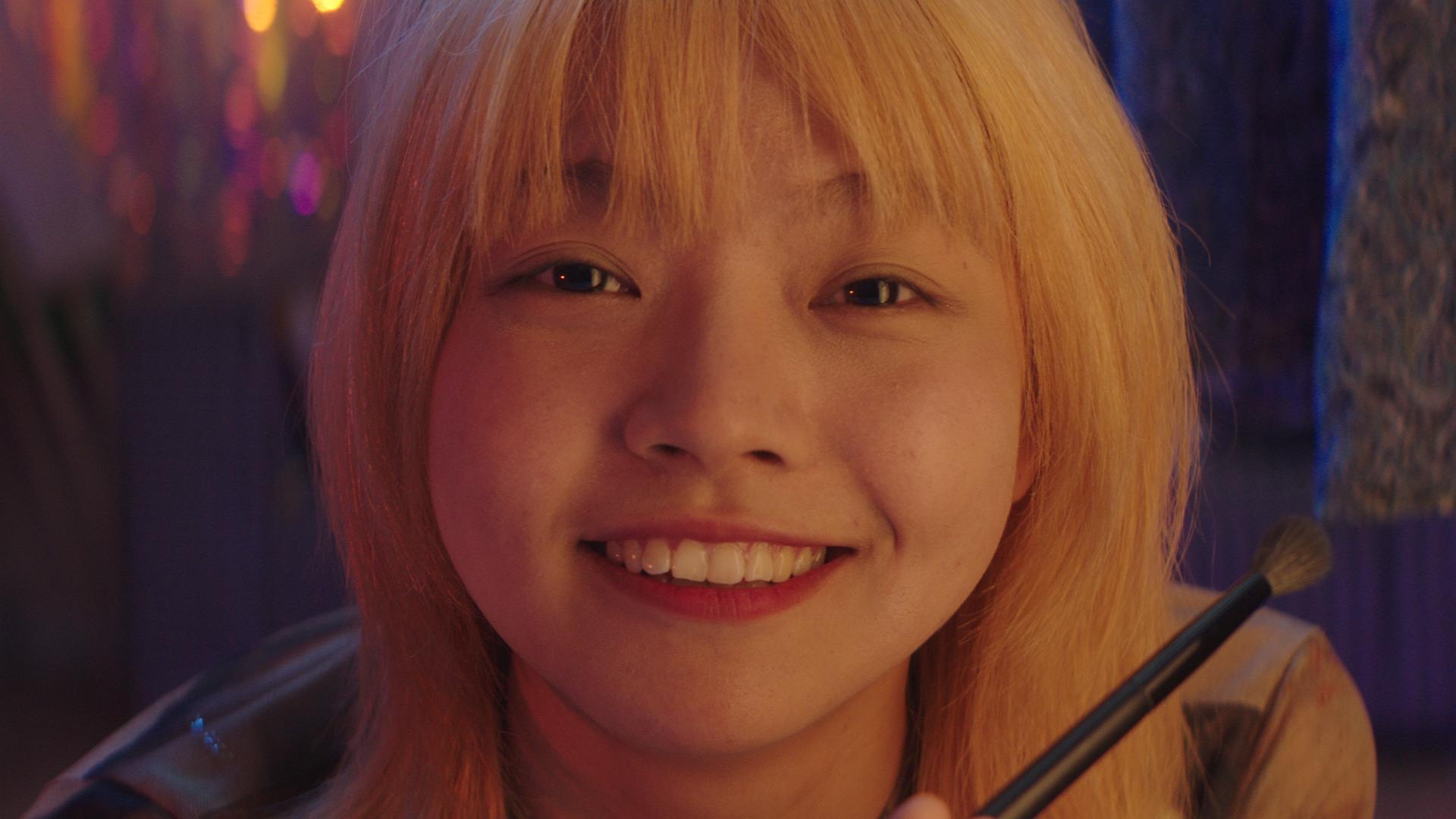 A smiling girl with a makeup brush