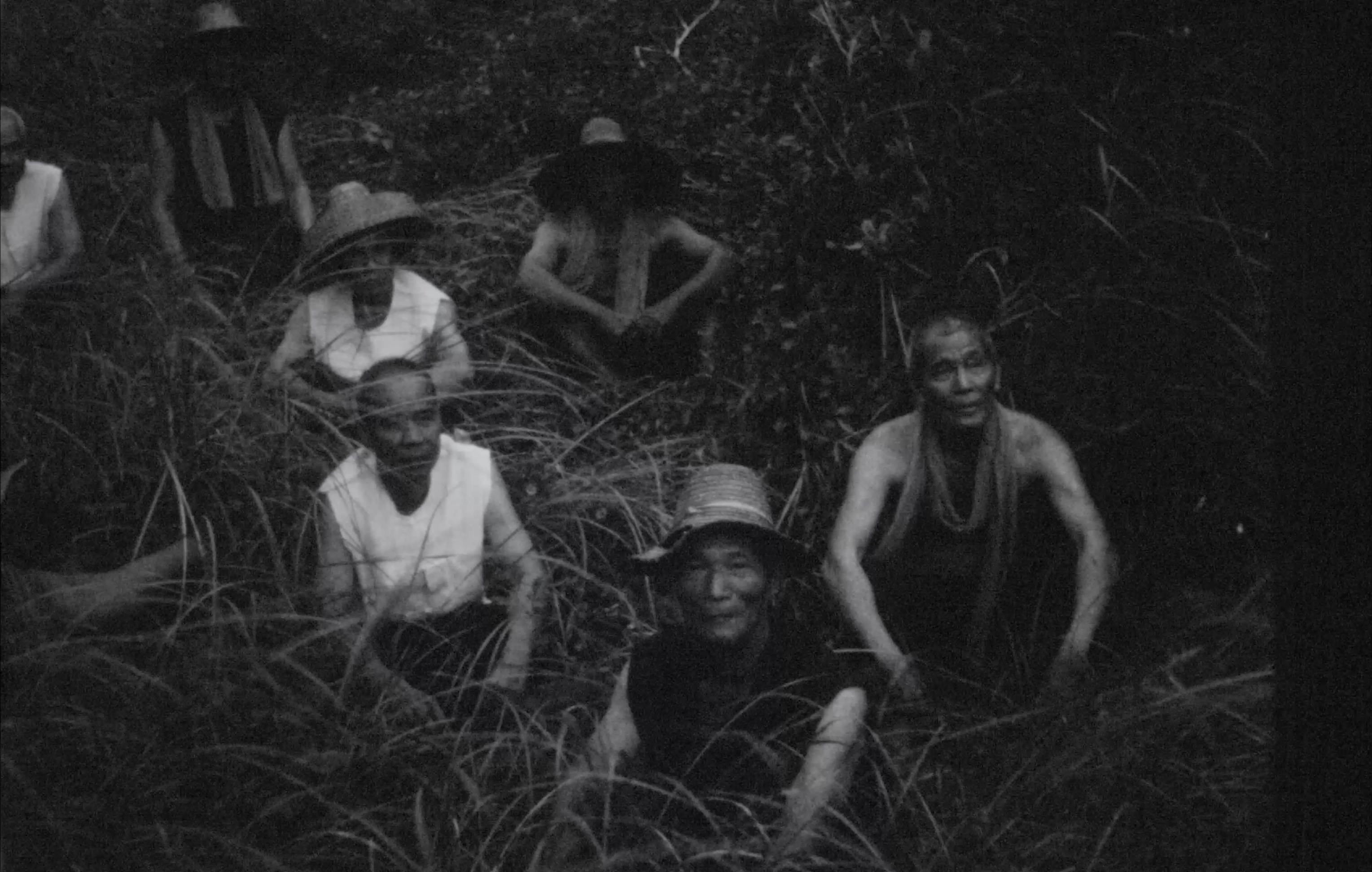 Villagers seated among tall grass