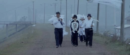 A funeral procession walking along a rural road