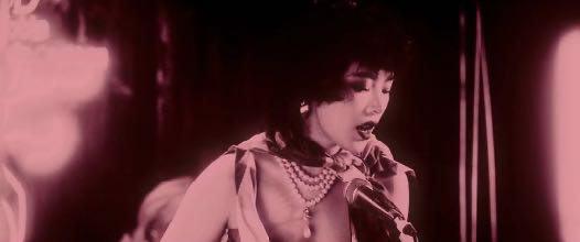 A singer performing beneath pink stage lights