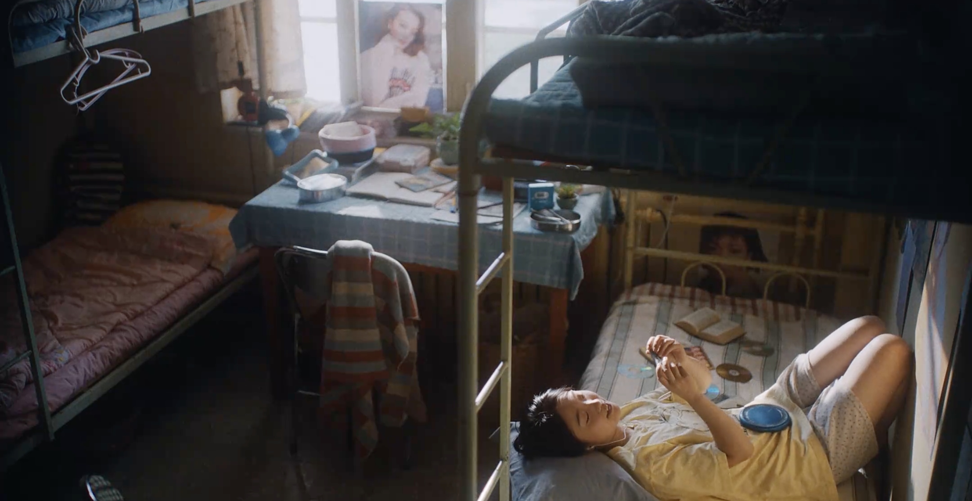 A young woman listening to music on a dormitory bed