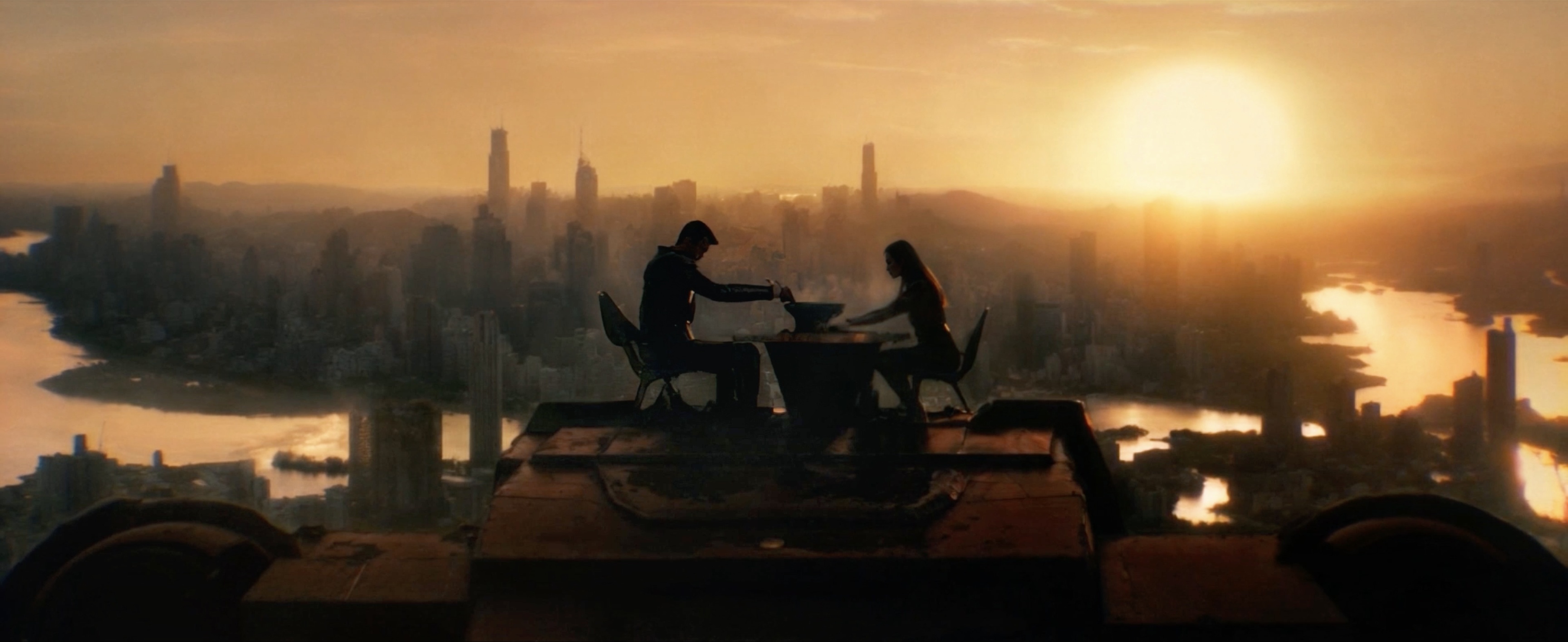 Two figures dining above a city at sunset