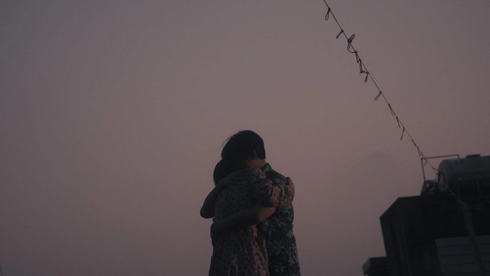 Two figures embracing on a rooftop