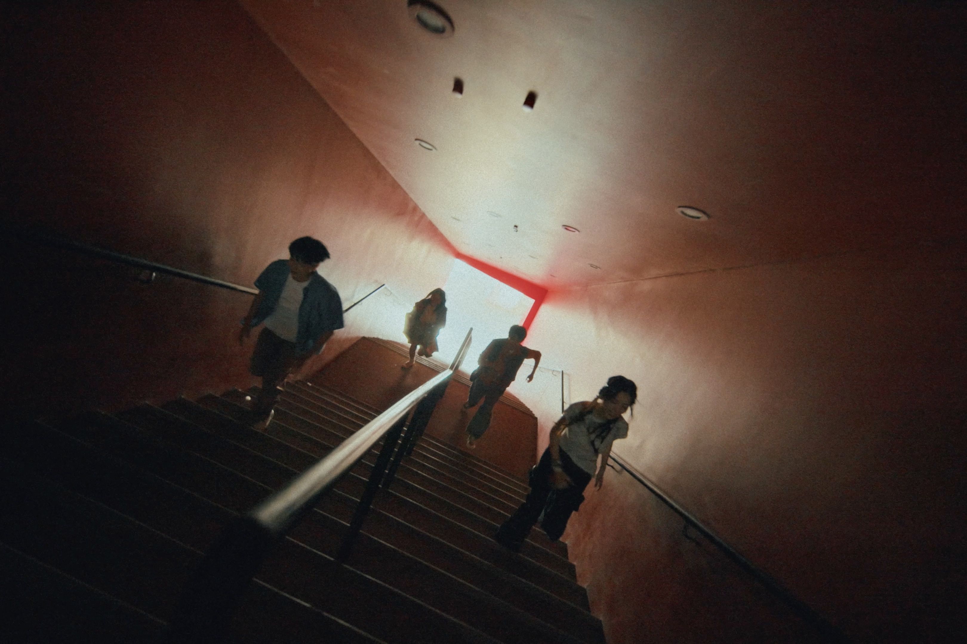 Four people running up a red stairway