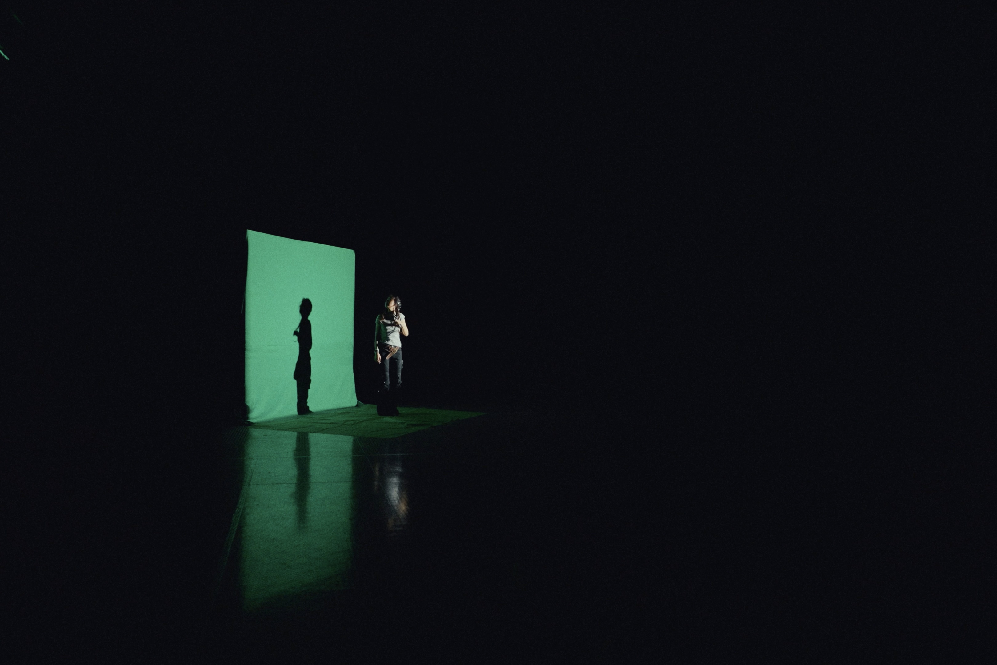 A performer beside a green illuminated backdrop