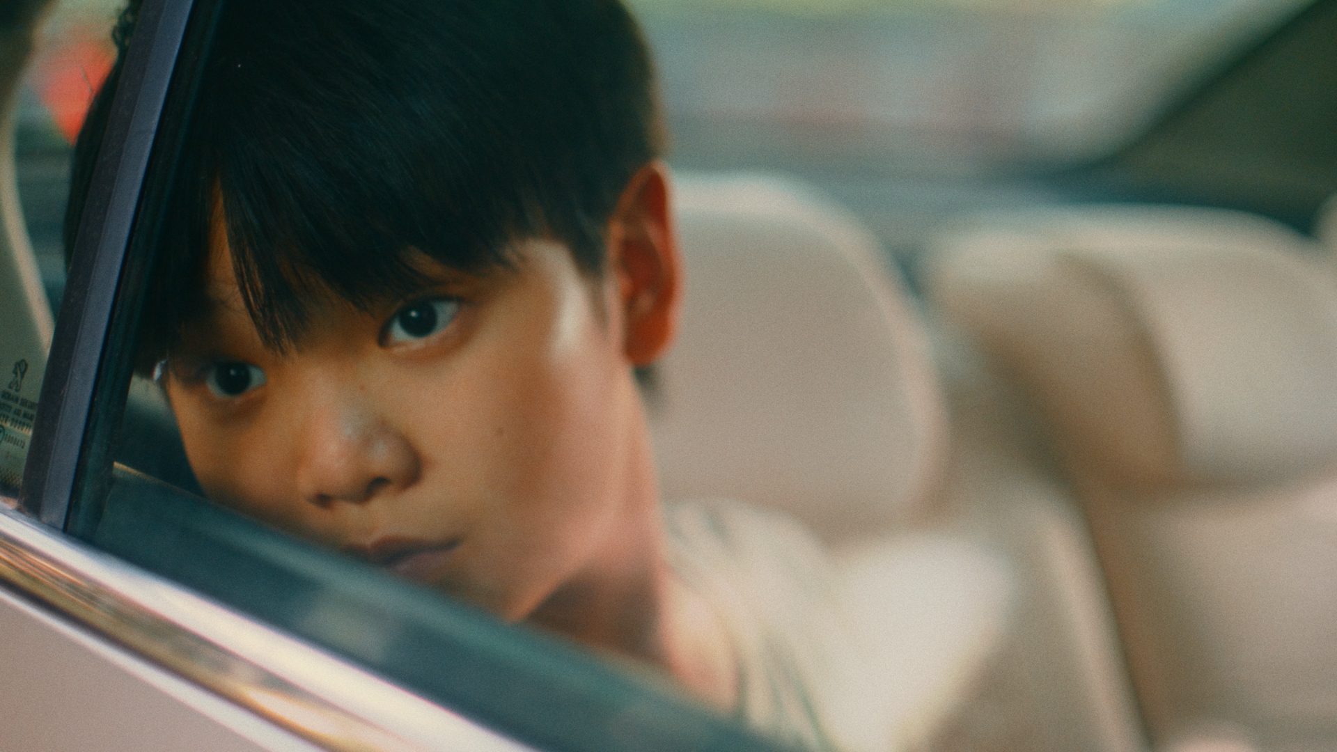 A boy looking through a car window