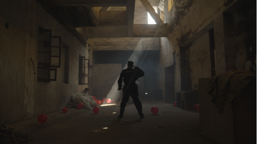 A figure beneath a shaft of light among red balloons