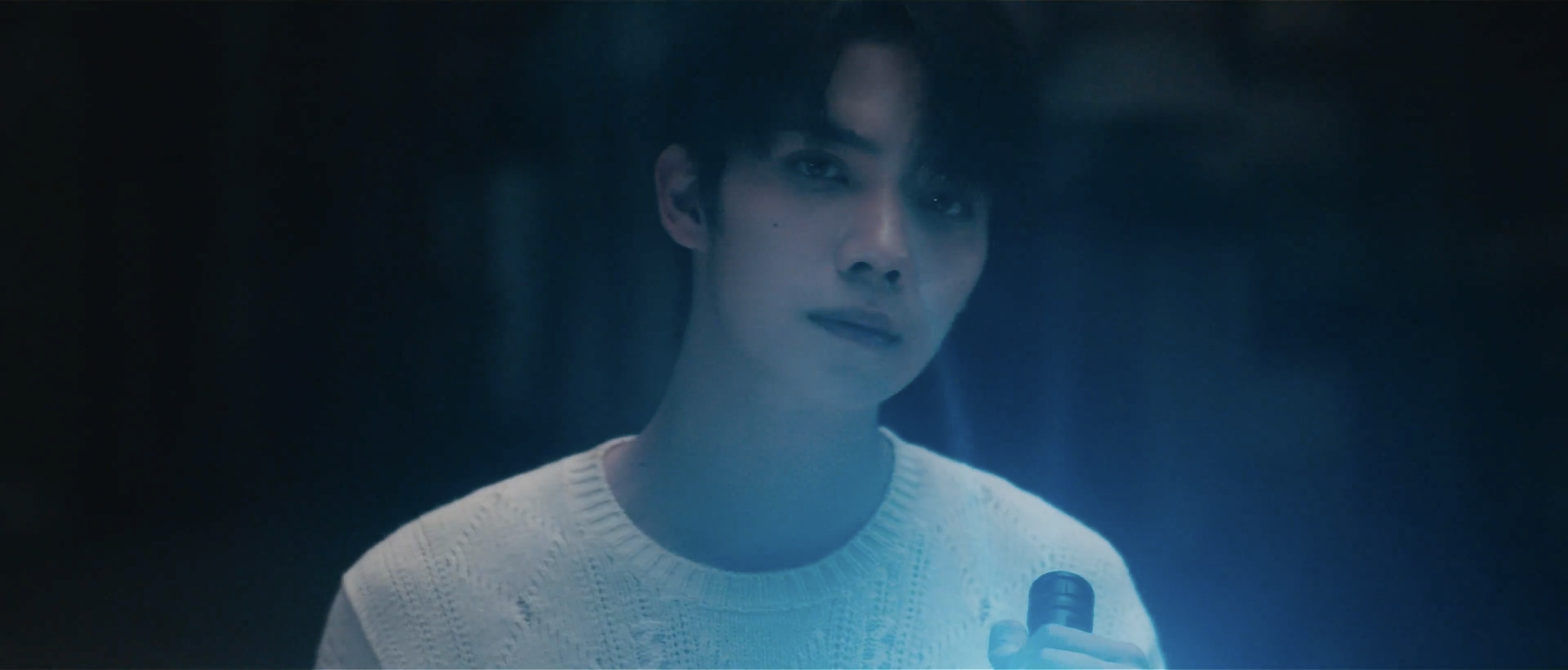 Luo Yizhou holding a flashlight in blue light